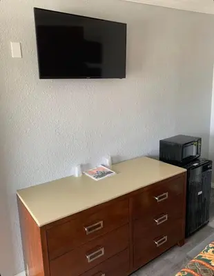 a tv on a wall above a dresser with a printer at Hi Rise Motel in Lynwood