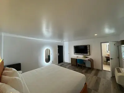 a bedroom with a bed and a desk with a television at Hotel Rudra - Hollywood in Los Angeles
