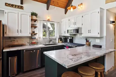 a kitchen with white cabinets and a counter with stools at Timeless Traditions Arrowhead home in Lake Arrowhead