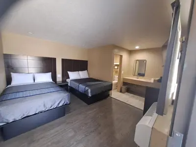 a hotel room with two beds and a television at American Inn i10 Rialto and Colton in Rialto