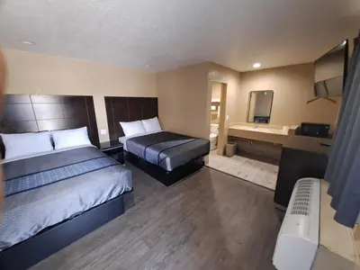 a hotel room with two beds and a television at American Inn i10 Rialto and Colton in Rialto