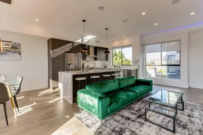 a living room with a green couch and a kitchen at Modern 4 Bedroom Masterpiece With Rooftop Deck in Los Angeles