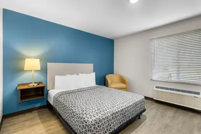 a bedroom with a bed and a blue wall at WoodSpring Suites Palmdale - Lancaster in Palmdale