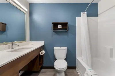 a bathroom with a white toilet and a blue wall at WoodSpring Suites Palmdale - Lancaster in Palmdale