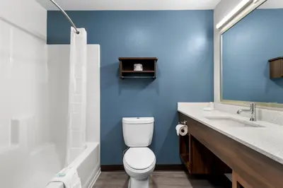 a bathroom with a white toilet and a blue wall at WoodSpring Suites Palmdale - Lancaster in Palmdale
