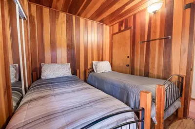 a bedroom with two beds in a wooden wall at Silver Rays - Game room with pool table & air hockey! Close to the slopes!! in Big Bear Lake