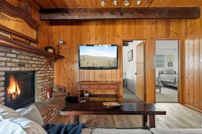 a living room with a fireplace and a tv at Pine Oaks Cabin in Lake Arrowhead