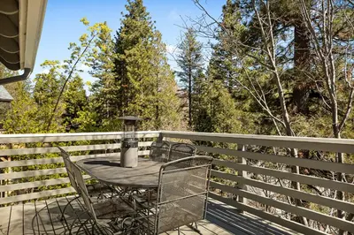 a patio with a table and chairs on a fence at Pine Oaks Cabin in Lake Arrowhead