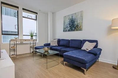 a living room with a blue couch and a table at The Carlton - Modern-Lux 2 Master Suites-Secure Bldg & Parking- 5 BLKS to Ocean Ave in Los Angeles