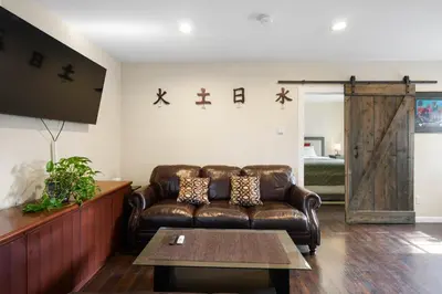 a living room with a leather couch and a table at 1 bd guest house in LA perfect for long term stay in Los Angeles