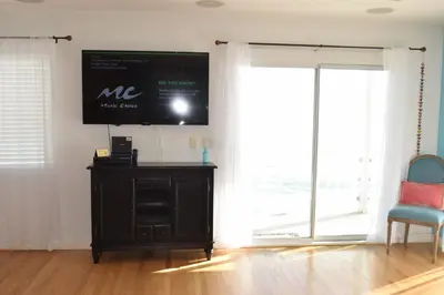 a living room with a tv on the wall and a chair at Malibu Private Beach Apartments in Malibu