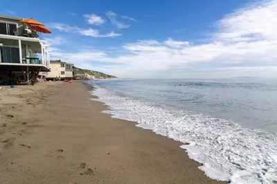 a beach with a building and the ocean at Malibu Private Beach Apartments in Malibu