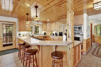 a kitchen with wooden cabinets and a counter with bar stools at Eagle point lake house #2471 in Big Bear Lake