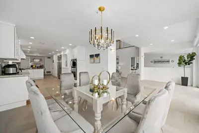 a dining room with a glass table and chairs at Luxury Waterfront Home in the Heart of the Harbor in Huntington Beach