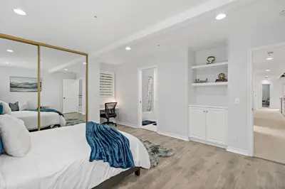 a white bedroom with a large bed and a mirror at Luxury Waterfront Home in the Heart of the Harbor in Huntington Beach
