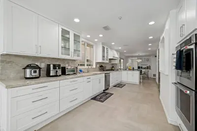 a large white kitchen with white cabinets and appliances at Luxury Waterfront Home in the Heart of the Harbor in Huntington Beach