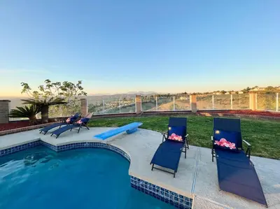 a swimming pool with chairs and a view of the ocean at Top of the World Anaheim View Home in Anaheim
