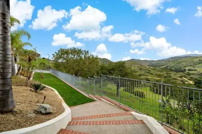 a fence in front of a walkway with mountains in the background at Luxury Oasis With Panoramic Views in Anaheim