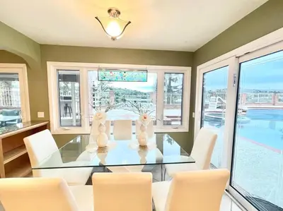a dining room with a glass table and white chairs at Stunning Panoramic Waterfront Pool Home Escape in Anaheim