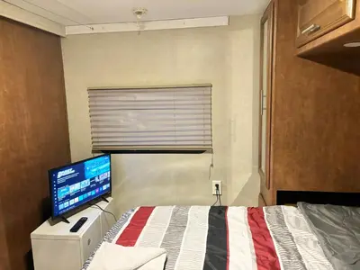 a bedroom with a bed with a computer monitor on it at Rooms in Modern RV Trailer Home in Los Angeles