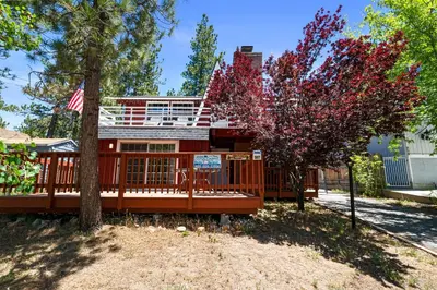 a house with a red fence and a tree at Chateau Rouge - Walk to Lake & Village, AC, Pet Friendly! in Big Bear Lake