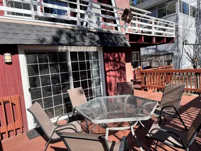 a patio with chairs and a glass table on a deck at Chateau Rouge - Walk to Lake & Village, AC, Pet Friendly! in Big Bear Lake
