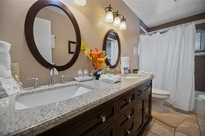a bathroom with a sink and two mirrors at Wanderlust - Hot Tub, Foosball, Ping Pong, Walk to Lake & Village! in Big Bear Lake