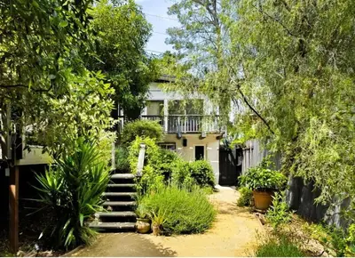 a house with a staircase in front of a yard at Zen Birds Nest of Topanga Boho Chic with Epic Deck in Topanga