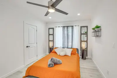 a bedroom with an orange bed with a ceiling fan at 2 Mi to Citadel Outlets! East LA Retreat Near I-5 in Los Angeles