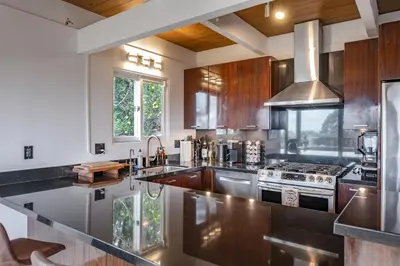 a kitchen with stainless steel appliances and wooden cabinets at Hollywood Hills Retreat with Panoramic View in Los Angeles