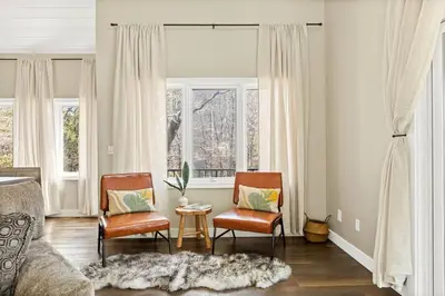 a living room with two chairs and a bed and windows at Oak Mountain Retreat, Hot Tub, & BBQ, Game Room! in Lake Arrowhead