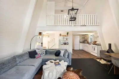 a living room with a blue couch and a kitchen at Scout's Lakehouse Retreat by Colby & Conrad in Lake Arrowhead