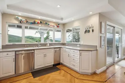 a large kitchen with white cabinets and a large window at Bouquet Cottage home in Thousand Oaks