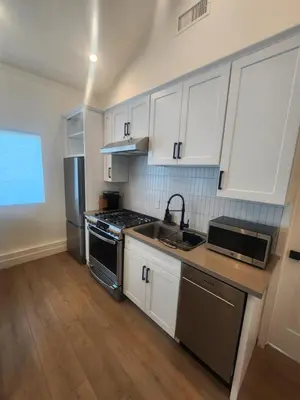 a kitchen with white cabinets and a sink and a stove at Ladera Retreat near Sofi Stadium, LAX, Beach in Los Angeles