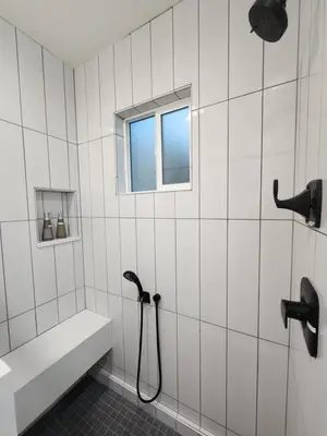 a white tiled bathroom with a shower and a window at Ladera Retreat near Sofi Stadium, LAX, Beach in Los Angeles