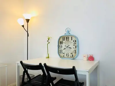 a table with two chairs and a clock on a wall at Coastal Comfort Homestay in Santa Monica in Los Angeles