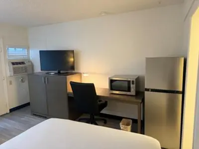 a room with a desk with a microwave and a refrigerator at MC Pacific Inn & Suites Torrance in Torrance