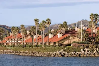 a building with red roofs and palm trees next to the water at Beautiful Resort in Harbortown Point ST near Marina Park in Ventura
