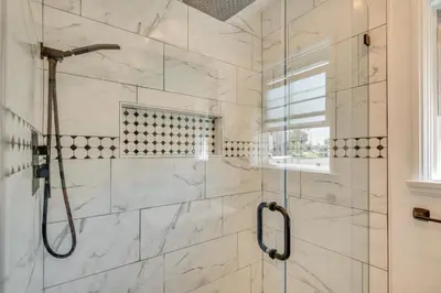 a bathroom with a shower with white marble tiles at 2 Mi to SoFi Stadium Updated Inglewood Home! in Los Angeles