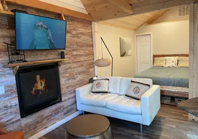 a living room with a couch and a tv on a wall at Bugsy's Hideout in Lake Arrowhead