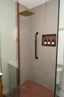 a shower with a glass door and some bottles at Adobe Inn in Monterey Park
