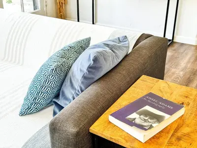 a couch with pillows and a book on a table at Serene and beautiful hillside retreat in Glendale