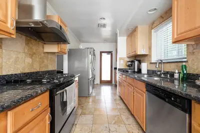 a kitchen with wooden cabinets and stainless steel appliances at Elegance Escape Sleeps 10 Pool with Jacuzzi in Los Angeles
