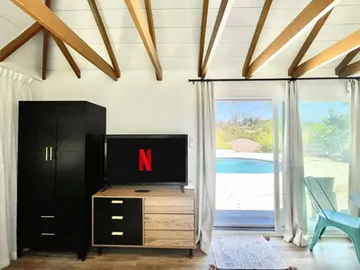 a tv on a dresser in a room with a sliding glass door at Sunny Days Tiny House with private entrance, pool and view in West Covina