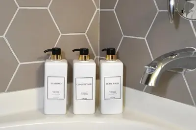 two white bottles ofodorizers sitting on a bathroom sink at Hollywood CHIC Studio with FREE parking in Los Angeles