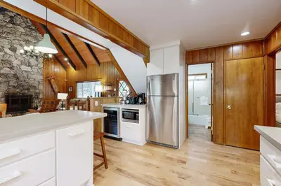a kitchen with white cabinets and a stainless steel refrigerator at Quiet Wooded Retreat in Lake Arrowhead