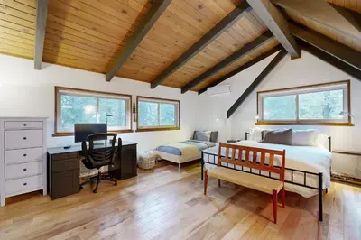 a bedroom with a bed and a desk with a computer at Quiet Wooded Retreat in Lake Arrowhead