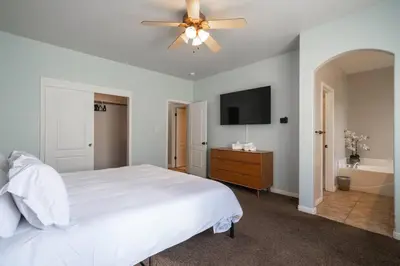 a bedroom with a white bed and a ceiling fan at Central Bliss near parks & shops in Bakersfield
