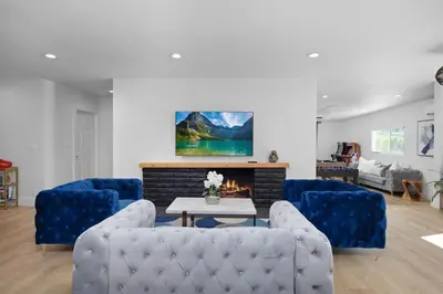 a living room with blue couches and a fireplace at NEW Lux 5BR Villa Near Disney, Knotts, LA, OC with Hot Tub & Games in Fullerton