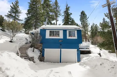 a blue tiny house in the snow at Cozy Bear Cottage - Walk to Lake & Village! in Big Bear Lake